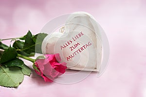 Heart of wood and a rose on a pink background, german text Alles