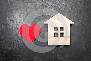 Heart and wooden house on a gray concrete background. The concept of a love nest, the search for new affordable housing for young