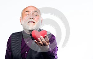 Heartbeat diagnostics and treatment. Health care. Senior bald head bearded man holding red toy heart in hands. Mature