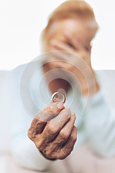 Heartbroken elderly woman holding a wedding ring