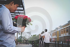 Heartbroken man holding bouquet of red roses feeling sad while s
