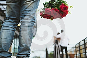Heartbroken man holding bouquet of red roses feeling sad while s