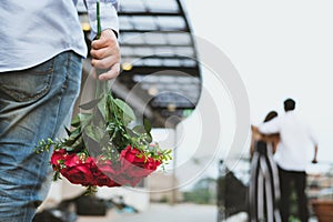 Heartbroken man holding bouquet of red roses feeling sad while s