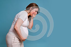 Heartburn in throat in pregnant woman, studio shot on blue background