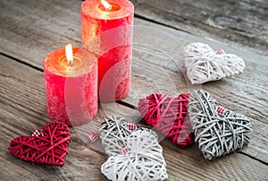 Hearts with burning candles on the wooden background