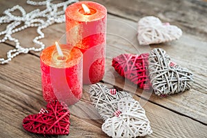 Hearts with burning candles on the wooden background