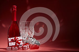 Hearts, champagne and flutes, gifts, disco balls on red background with copy space. Festive party. 14 February. Valentine`s Day