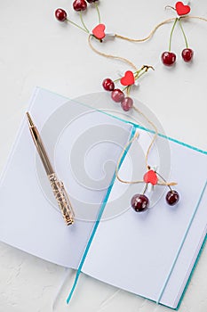 Hearts and cherry. Dreaming theme about love. An open notebook is on a white background.wooden red heart, a declaration