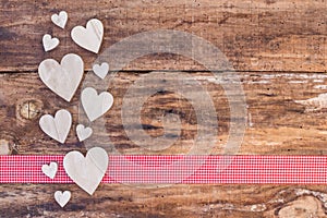 Hearts decoration on red ribbon border and wooden background