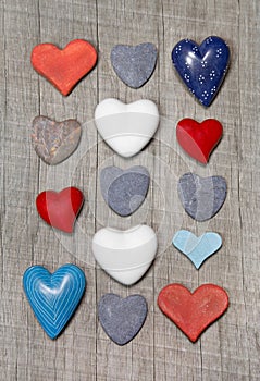 Hearts in different colors on wooden background.