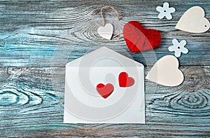 Hearts, flowers and an envelope on a wooden background.