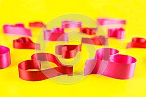 Hearts made from pink and red, satin ribbon on yellow background. Valentines Day concept.