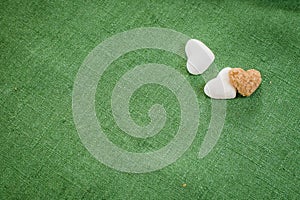 Hearts made of refined white sugar and brown sugar lie on green linen cloth