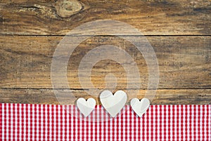 Hearts with red checkered fabric on brown wood.