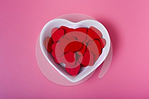 Hearts in a saucer in the shape of a heart on a pink background