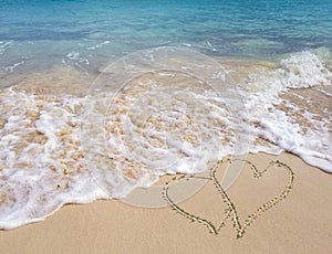 Hearts in seashore sand with ocean surf