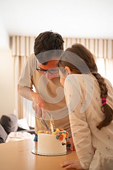 A heartwarming scene as a child shares a moment with her father while they cut into a whimsical unicorn birthday cake