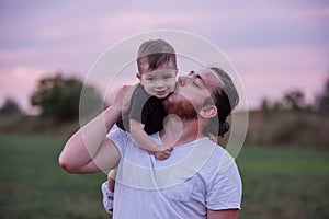 Heartwarming scene of diversity father carrying smiling son on shoulders at twilight, Fathers day