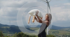 This heartwarming video captures a joyful scene of a happy little girl standing in a field, with wind turbines wind