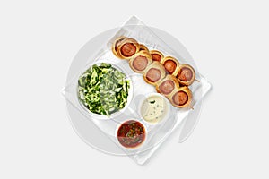 Hearty breakfast with baked sausage rolls, salad, and dipping sauces