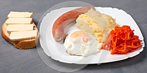Hearty delicious lunch. toasted egg sausage and potato with a cheesy sandwich on a white plate. gray background close-up
