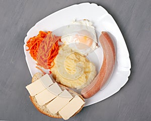 Hearty delicious lunch. toasted egg sausage and potato with a cheesy sandwich on a white plate. gray background close-up top view