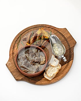 Hearty and fatty lunch. Meat broth with garnish on round wooden cutting board. Pot of rich meat soup with pork or lamb