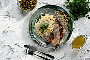 A hearty meal on the table, spaghetti with fried pork chunks, green canned peas and watercress grass. Next to the sauce