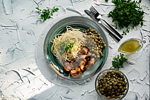 A hearty meal on the table, spaghetti with fried pork chunks, green canned peas and watercress grass. Next to the sauce