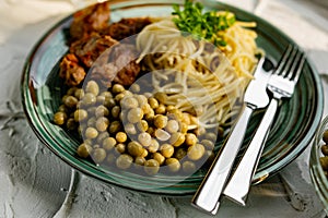 A hearty meal on the table, spaghetti with fried pork chunks, green canned peas and watercress grass. Next to the sauce