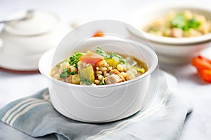 hearty vegetable barley soup in a white bowl