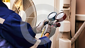 Heat and Air Conditioning, HVAC system service technician using measuring manifold gauge checking refrigerant and filling