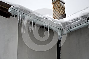 The heat from the house passes through the roof and melts the snow. it freezes in the eaves of the roof and forms icicles. repel t