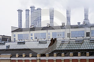 Heat station in the city. Smoking pipes against blue sky. Aluminum pipes of old Industrial building of factory