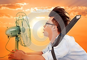 The heat wave is coming,business man holding a electric fan