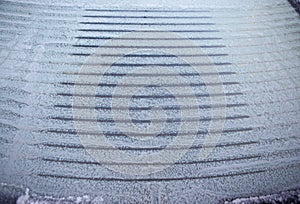 Heated, ice-covered rear window of the car when defrosting on a winter morning