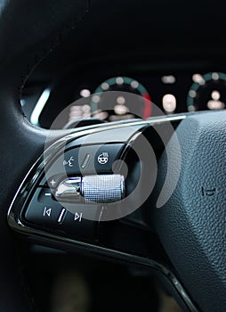 Heated steering wheel control buttons with blurred dashboard in car interior