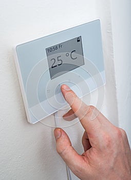Heating concept. Man is adjusting temperature in room on electronic thermostat control.