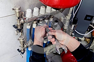 Heating engineer installing modern heating system in boiler room.