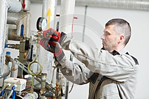 Heating engineer or plumber in boiler room installing or adjusting manometer