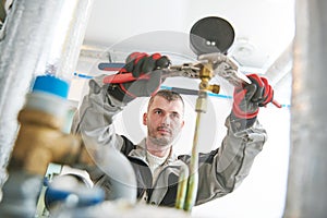 Heating engineer or plumber in boiler room installing or adjusting manometer