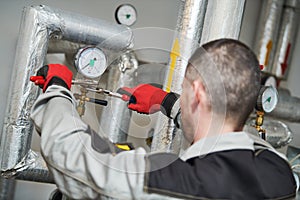 Heating engineer or plumber in boiler room installing or adjusting manometer