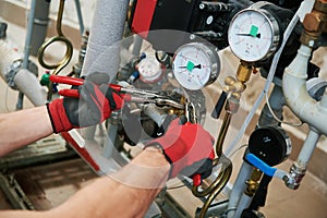 Heating engineer or plumber in boiler room installing pipeline manometer