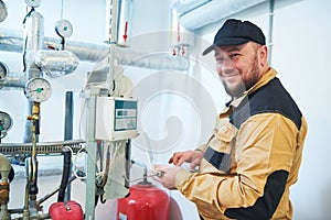 Heating engineer or plumber inspector in boiler room taking readouts or adjusting meter