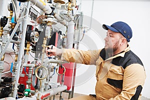 Heating engineer or plumber inspector in boiler room taking readouts or adjusting meter