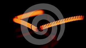 Heating a lamp spiral wire to orange colore, close-up on a dark background, abstraction, soft focus