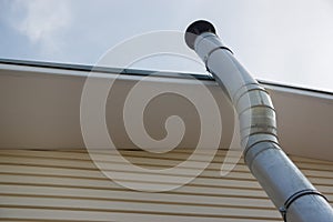 Heating pipe under the roof of a house covered with siding against the sky