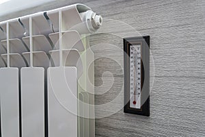 Heating radiator thermostat set to low temperature room thermometer for saving money at heating costs. Energy crisis