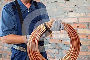 Heating red electrical cable in hands of male electrician technician dressed in overalls.