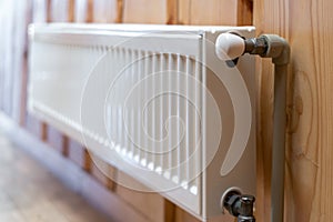 White modern radiator  on wooden wall in house with cozy interior